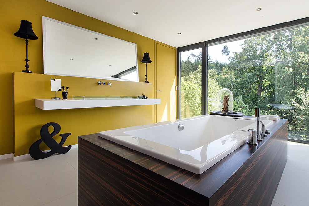 Exempel på ett mellanstort modernt badrum, med ett platsbyggt badkar, gula väggar, ett nedsänkt handfat och bänkskiva i glas