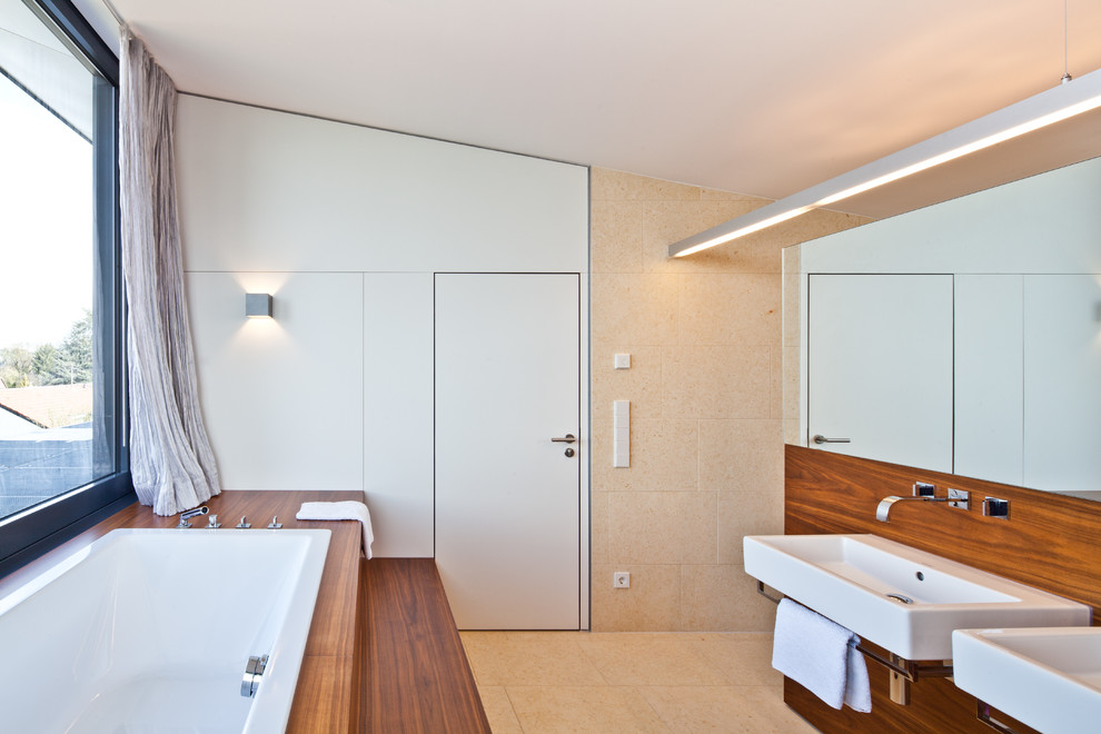Стильный дизайн: ванная комната среднего размера в современном стиле с накладной ванной, бежевыми стенами, полом из керамической плитки, подвесной раковиной и бежевым полом - последний тренд