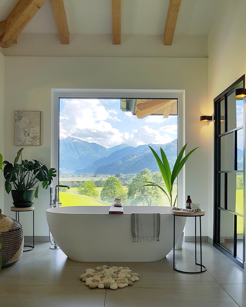 Cette photo montre une salle de bain principale scandinave avec une baignoire indépendante, un mur beige et un sol beige.