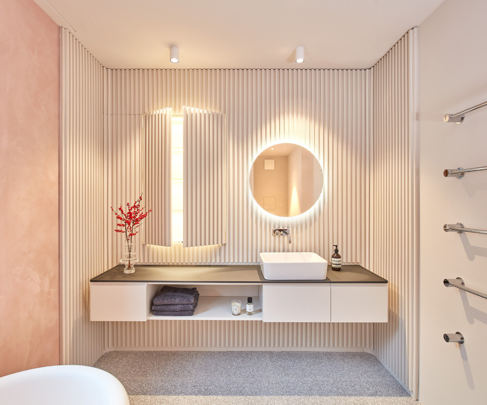 Design ideas for a large contemporary shower room bathroom in Munich with white cabinets, a freestanding bath, a built-in shower, a wall mounted toilet, pink walls, terrazzo flooring, a vessel sink, wooden worktops, grey floors, an open shower, black worktops and flat-panel cabinets.