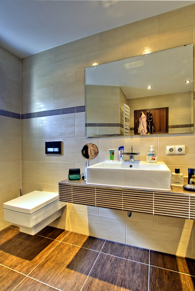 Immagine di una stanza da bagno design con WC sospeso, piastrelle beige e lavabo a bacinella
