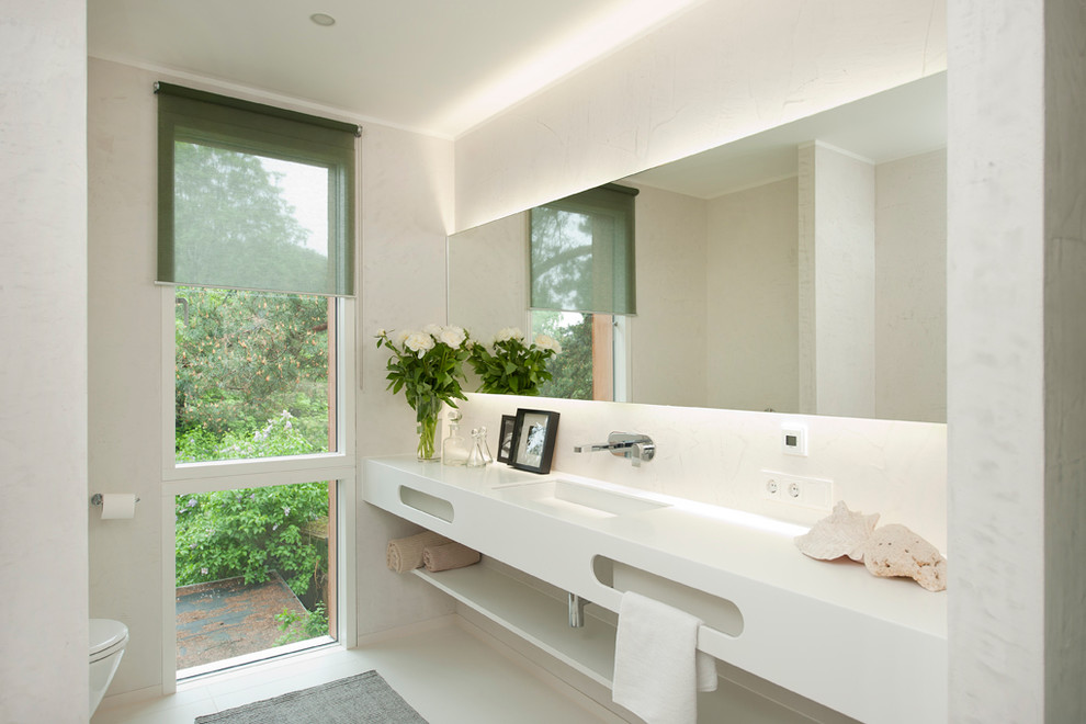 Пример оригинального дизайна: ванная комната в современном стиле с белыми стенами и монолитной раковиной