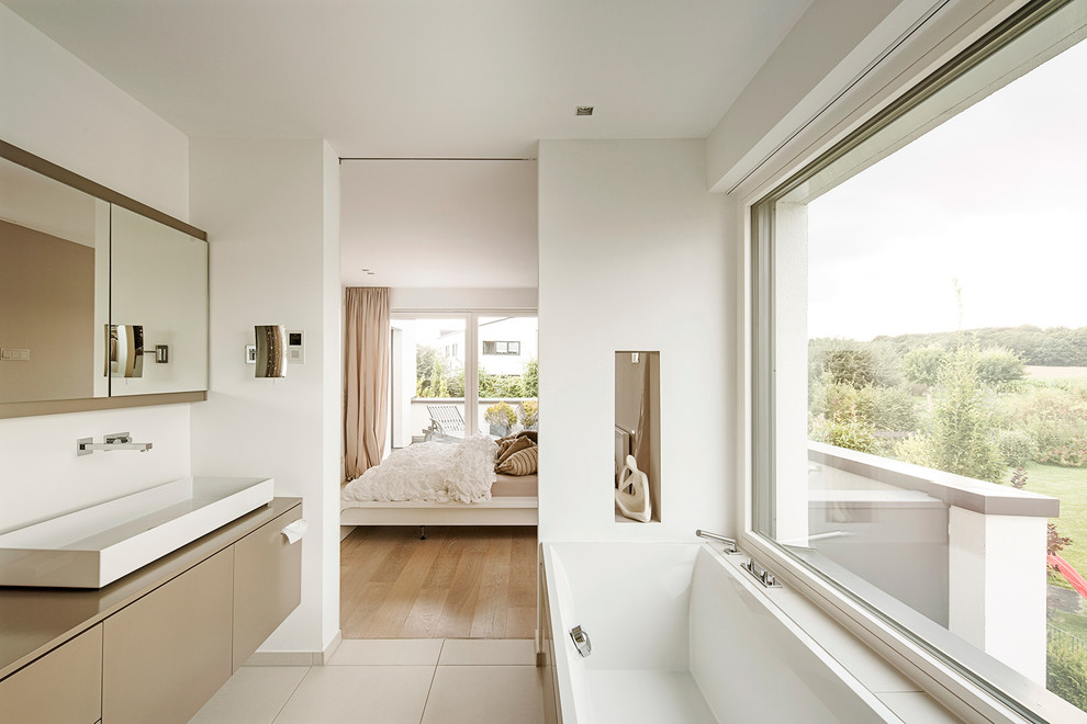 На фото: главная ванная комната среднего размера в стиле модернизм с настольной раковиной, плоскими фасадами, бежевыми фасадами, накладной ванной, белыми стенами и бежевой плиткой