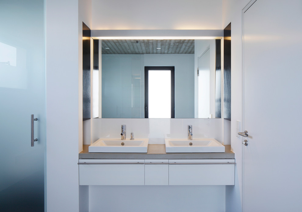 Modernes Badezimmer mit flächenbündigen Schrankfronten, weißen Schränken, weißer Wandfarbe, Aufsatzwaschbecken, weißen Fliesen und Beton-Waschbecken/Waschtisch in Dortmund