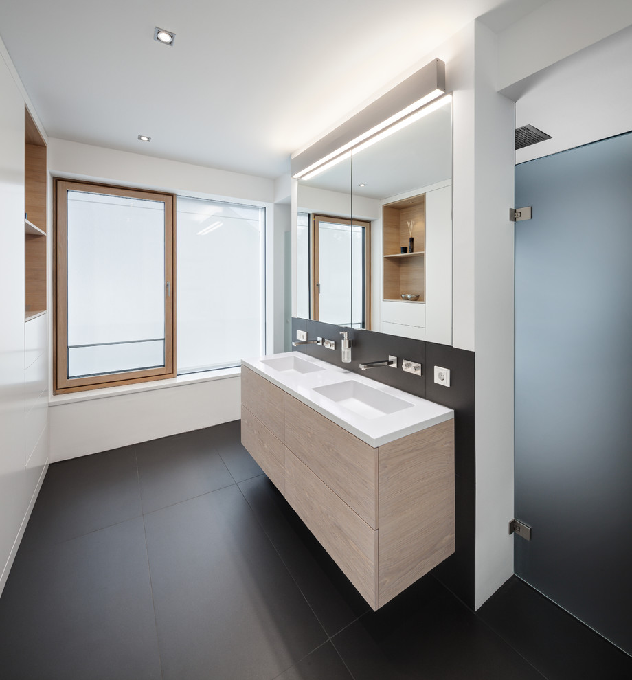 Exempel på ett mellanstort modernt en-suite badrum, med släta luckor, en kantlös dusch, svart kakel, vita väggar, skåp i ljust trä och ett integrerad handfat