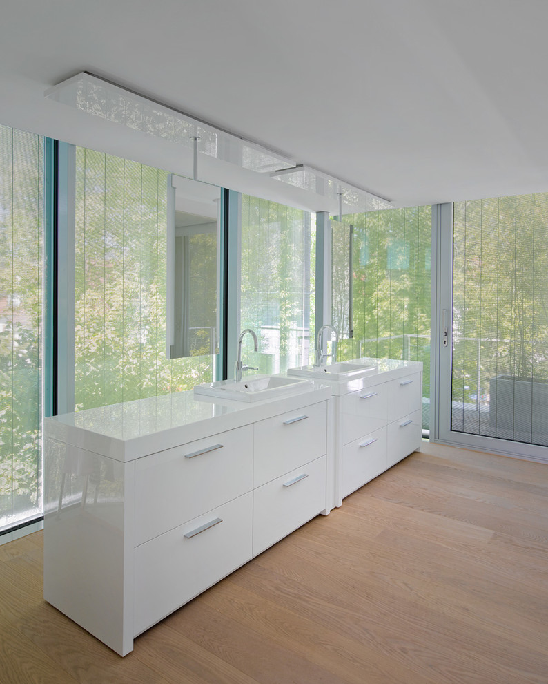 Großes Modernes Badezimmer mit Einbauwaschbecken, flächenbündigen Schrankfronten, weißen Schränken und braunem Holzboden in Berlin