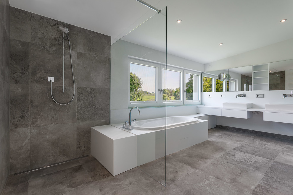 Пример оригинального дизайна: огромная главная ванная комната в современном стиле с настольной раковиной, плоскими фасадами, белыми фасадами, накладной ванной, душем без бортиков, серой плиткой, плиткой из листового камня и белыми стенами