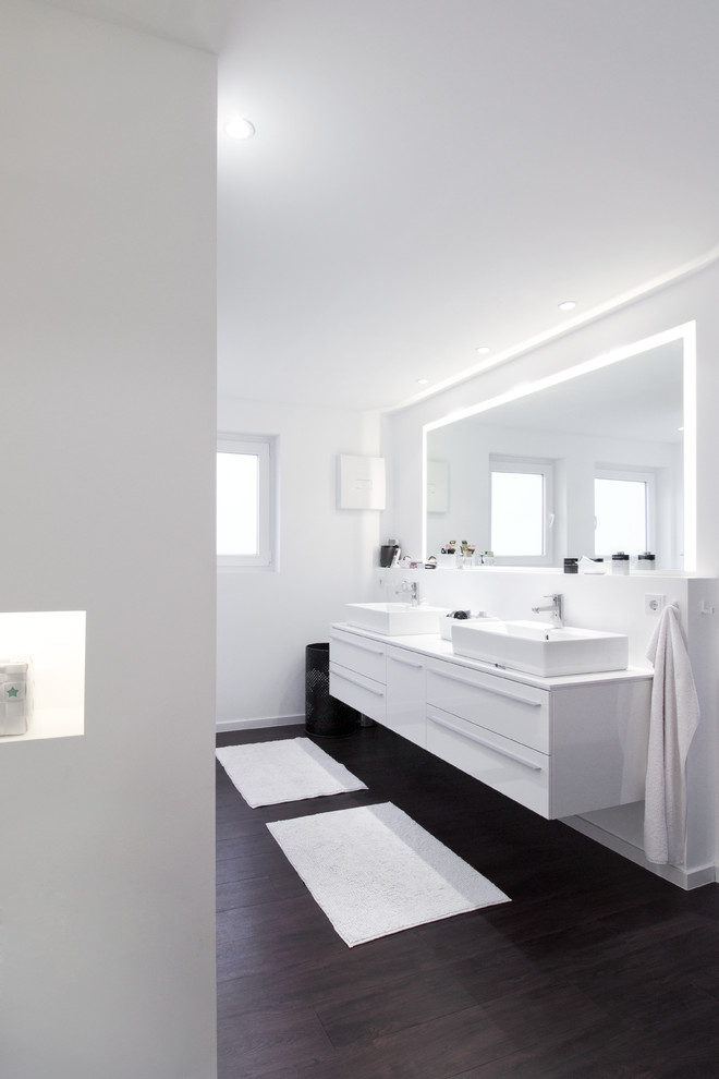 Идея дизайна: ванная комната среднего размера в современном стиле с темным паркетным полом, настольной раковиной и зеркалом с подсветкой