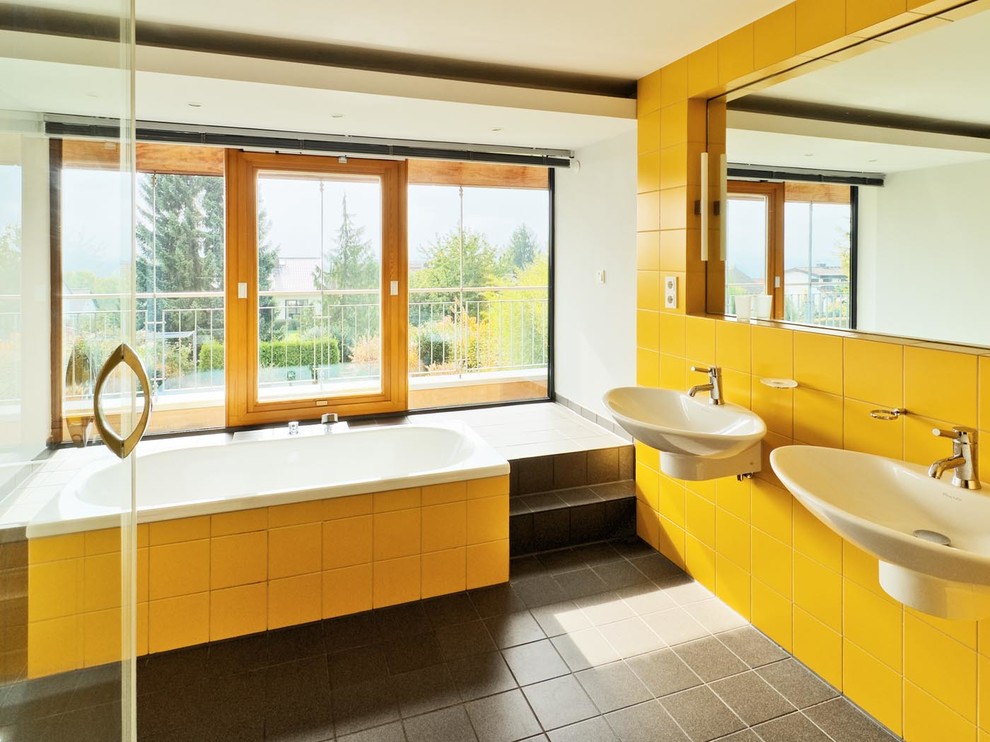 Cette image montre une grande salle de bain grise et jaune design avec un lavabo suspendu, une baignoire posée, un carrelage jaune et un mur blanc.