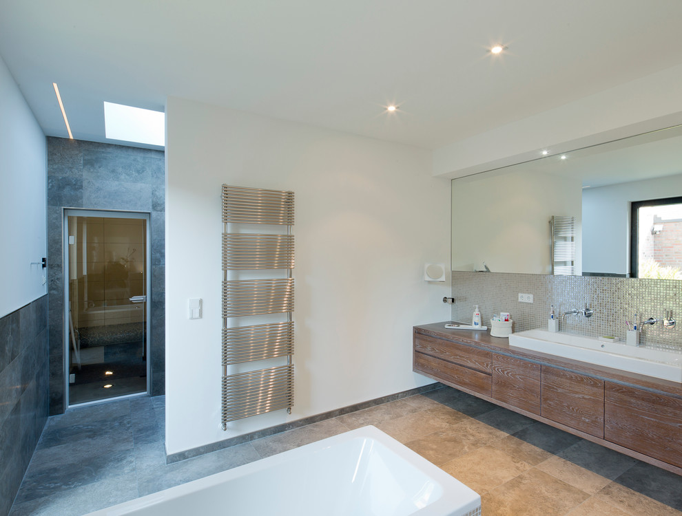 Foto på ett funkis en-suite badrum, med kakel i metall, ett avlångt handfat, släta luckor, skåp i mellenmörkt trä, träbänkskiva, en dusch i en alkov, vita väggar och ett fristående badkar