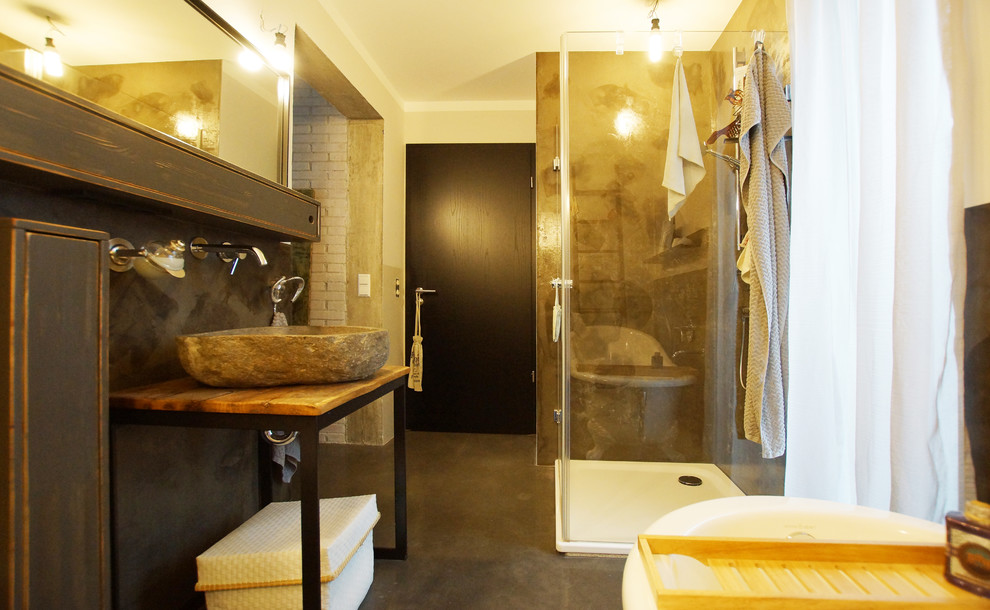 Design ideas for a medium sized rustic shower room bathroom in Other with a freestanding bath, open cabinets, a corner shower, beige walls, concrete flooring, a vessel sink, wooden worktops, black floors and a hinged door.