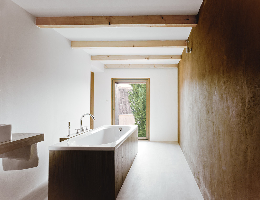 Réalisation d'une salle de bain minimaliste de taille moyenne avec une vasque, un plan de toilette en bois, sol en béton ciré, une baignoire indépendante et un mur marron.