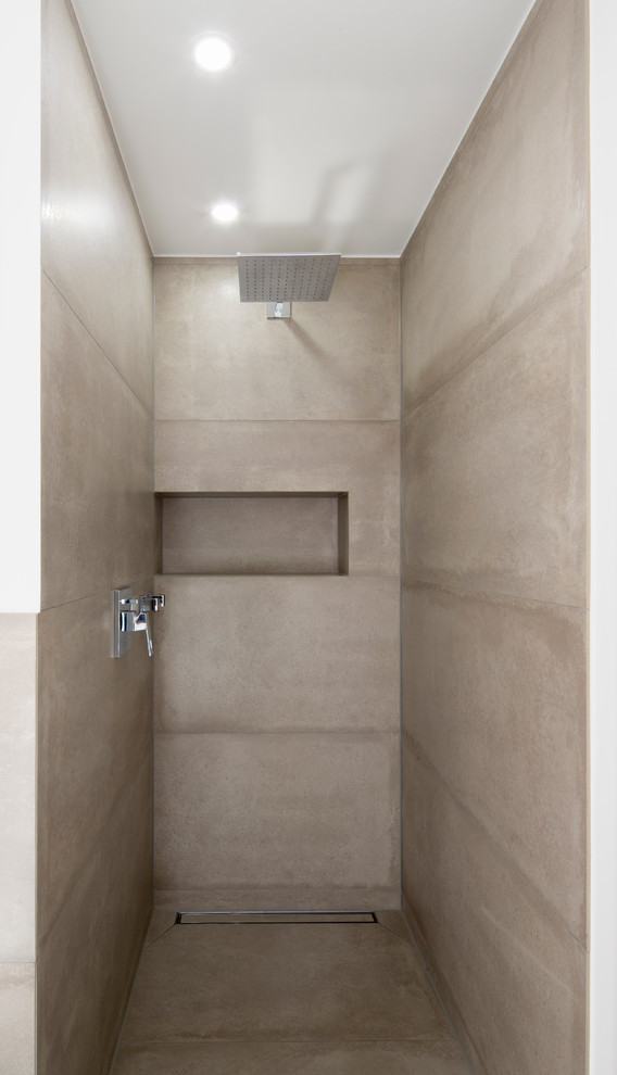На фото: ванная комната среднего размера в современном стиле с душем в нише, бежевой плиткой, бетонным полом и серыми стенами с