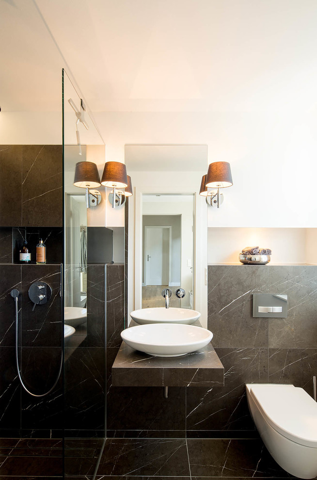 Mittelgroßes Modernes Badezimmer mit Wandtoilette, weißer Wandfarbe, Marmorboden, Aufsatzwaschbecken und schwarzen Fliesen in Düsseldorf
