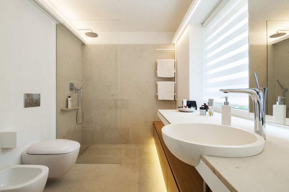 Idéer för ett litet modernt badrum med dusch, med släta luckor, skåp i ljust trä, en vägghängd toalettstol, grå kakel, vita väggar, ett nedsänkt handfat, kalkstensgolv, bänkskiva i kalksten, en dusch i en alkov och kakelplattor