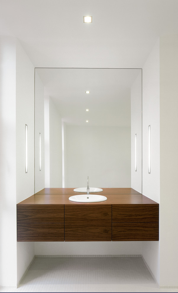 Cette photo montre une salle de bain tendance en bois foncé avec un placard à porte plane, un mur blanc, un sol en carrelage de terre cuite, un lavabo posé, un plan de toilette en bois, un carrelage gris et mosaïque.