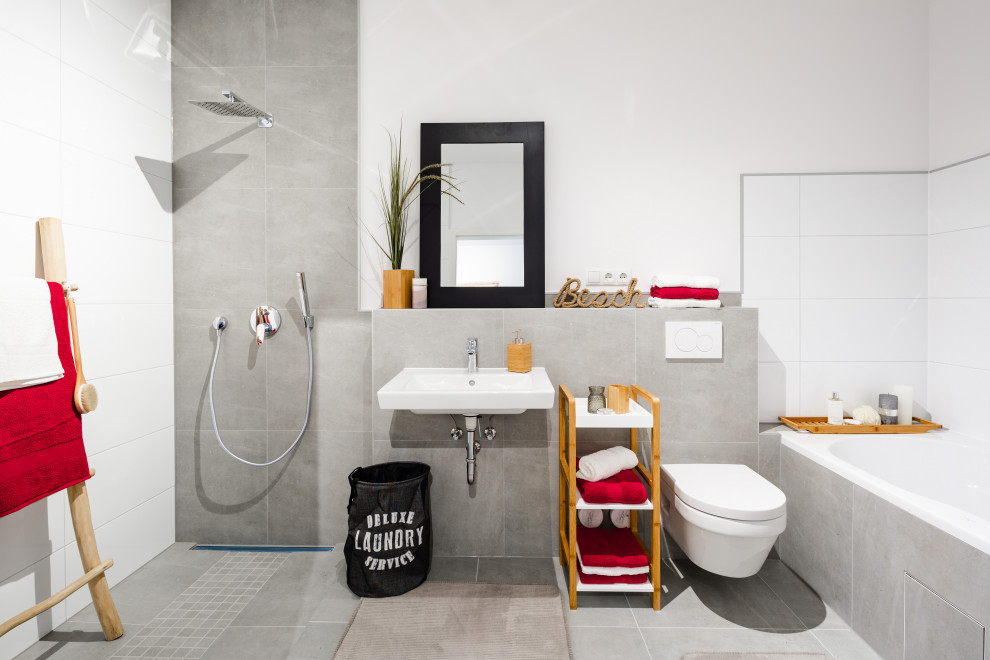 Modernes Badezimmer mit Einbaubadewanne, grauen Fliesen, weißer Wandfarbe, Wandwaschbecken, grauem Boden und Einzelwaschbecken in Köln