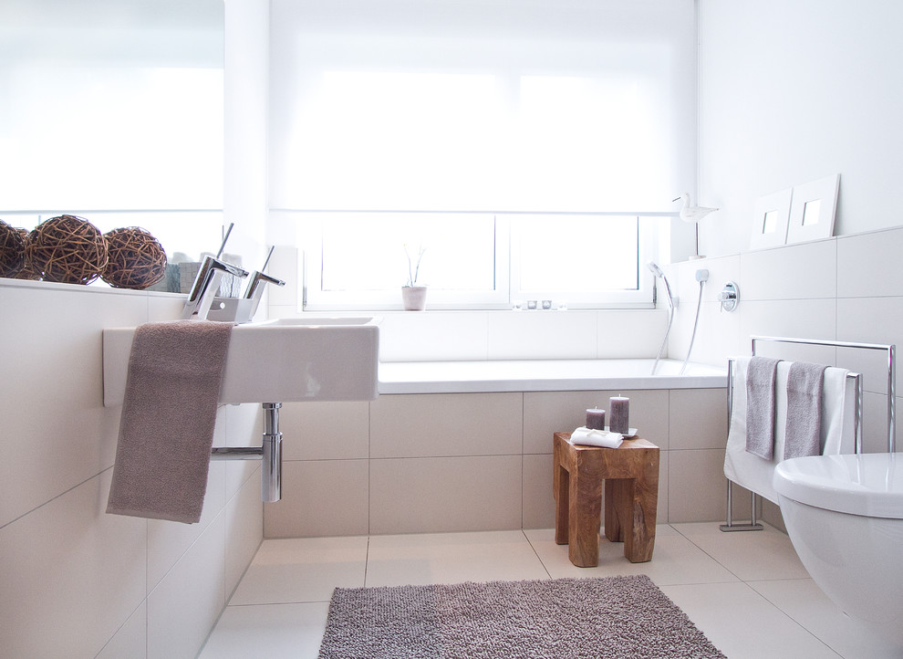 Inspiration pour une salle de bain design de taille moyenne avec une baignoire posée, un carrelage beige, un carrelage de pierre et un lavabo suspendu.