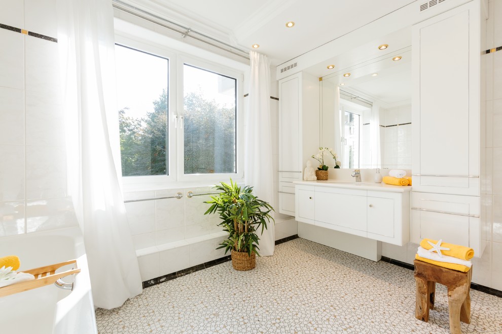 На фото: ванная комната в стиле неоклассика (современная классика) с плоскими фасадами, белыми фасадами, угловой ванной, белой плиткой, белыми стенами, полом из мозаичной плитки, душевой кабиной, врезной раковиной, бежевым полом и белой столешницей