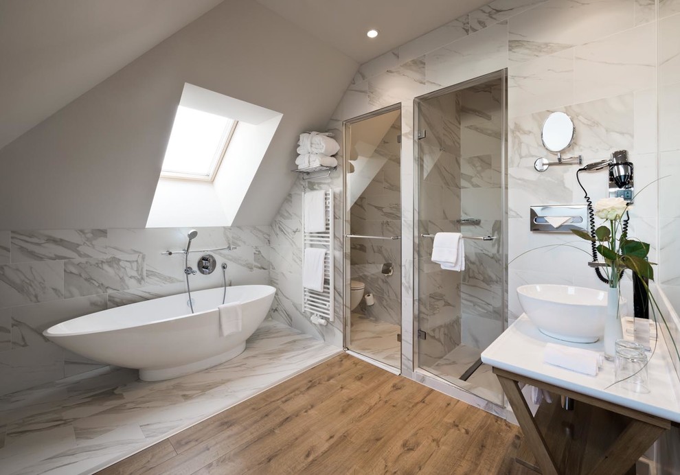 Diseño de cuarto de baño principal contemporáneo de tamaño medio con bañera exenta, baldosas y/o azulejos blancos, lavabo sobreencimera, ducha empotrada, suelo de madera en tonos medios, ducha con puerta con bisagras y ventanas
