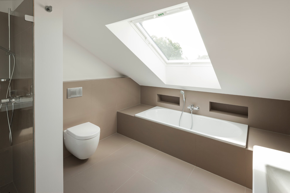 Modern inredning av ett badrum, med ett väggmonterat handfat, en kantlös dusch, en vägghängd toalettstol, beige kakel, keramikplattor, vita väggar och klinkergolv i keramik