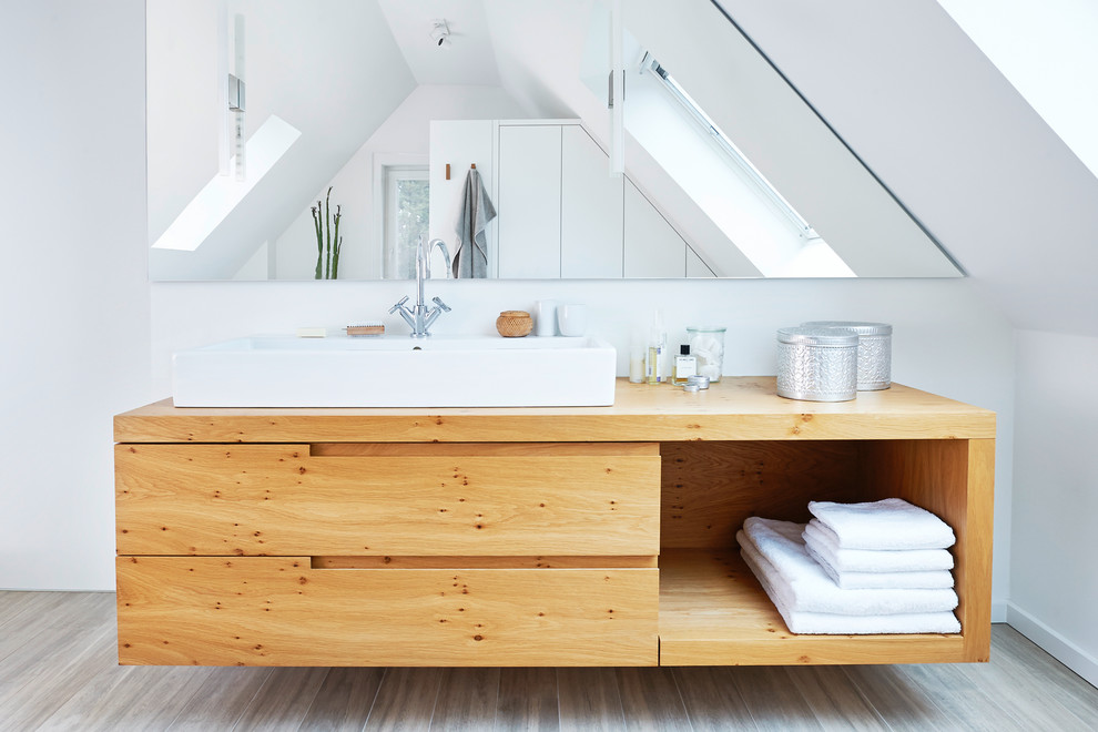 Modernes Badezimmer mit flächenbündigen Schrankfronten, braunen Schränken, weißer Wandfarbe, braunem Holzboden, Aufsatzwaschbecken, Waschtisch aus Holz und braunem Boden in Hamburg