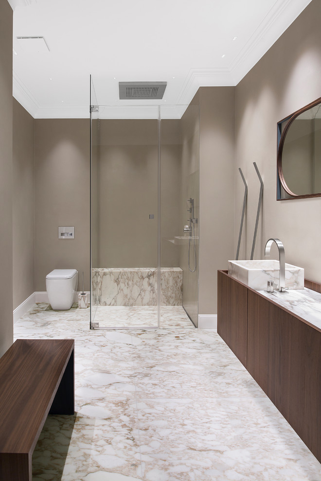 Свежая идея для дизайна: большая ванная комната в классическом стиле с плоскими фасадами, душем без бортиков, мраморным полом, душевой кабиной, мраморной столешницей, темными деревянными фасадами, раздельным унитазом, коричневыми стенами, настольной раковиной, белым полом, душем с распашными дверями и белой столешницей - отличное фото интерьера