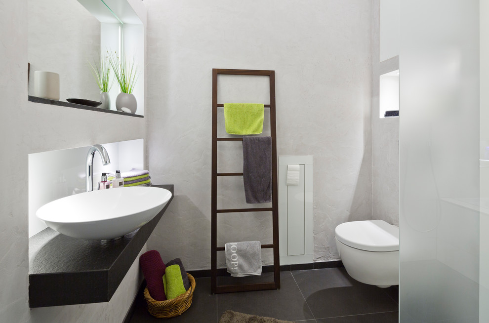 Example of a small trendy master gray tile and ceramic tile ceramic tile bathroom design in Cologne with flat-panel cabinets, white cabinets, a two-piece toilet, gray walls, a vessel sink and granite countertops