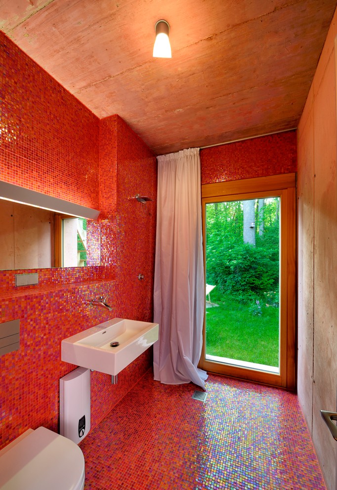 Imagen de cuarto de baño contemporáneo pequeño con ducha abierta, sanitario de pared, baldosas y/o azulejos rojos, baldosas y/o azulejos en mosaico, paredes rojas, suelo con mosaicos de baldosas, aseo y ducha, lavabo suspendido y ducha abierta