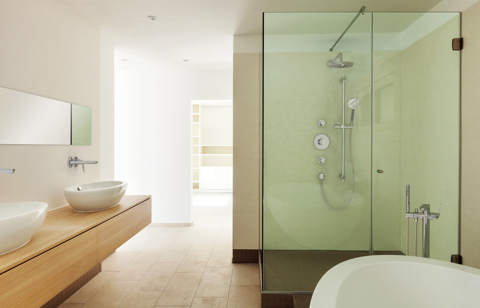 Réalisation d'une grande salle de bain design en bois brun avec un placard à porte plane, une baignoire indépendante, une douche d'angle, un mur blanc, un sol en calcaire, une vasque et un plan de toilette en bois.