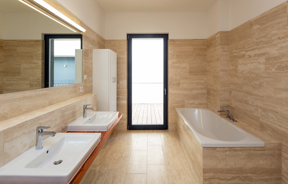 Modernes Badezimmer mit Einbauwaschbecken, Einbaubadewanne, beigen Fliesen und Waschtisch aus Holz in Leipzig