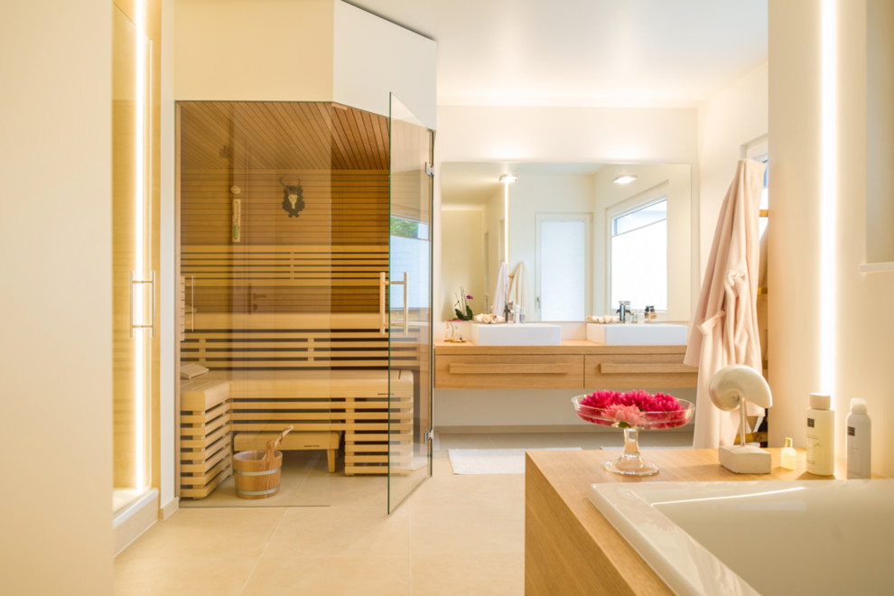 Idée de décoration pour un sauna design en bois clair de taille moyenne avec un placard à porte plane, une baignoire posée, un mur beige, une vasque, un plan de toilette en bois, un sol beige et un plan de toilette beige.