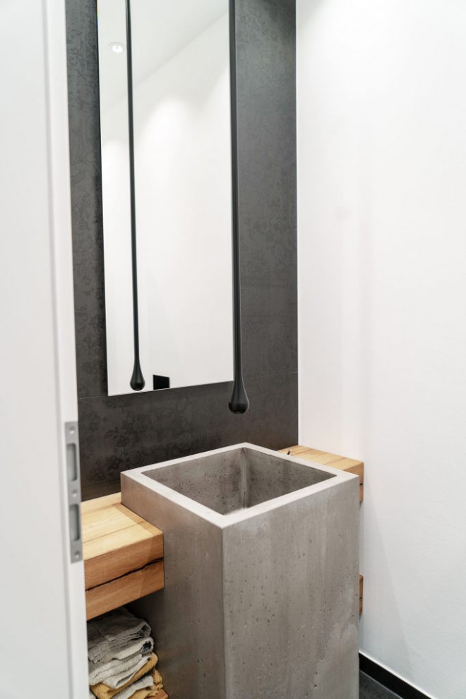 Aménagement d'une petite salle de bain principale moderne avec des portes de placard grises, un carrelage noir, un mur noir, un lavabo de ferme, un plan de toilette en béton, un plan de toilette marron, meuble simple vasque et meuble-lavabo sur pied.