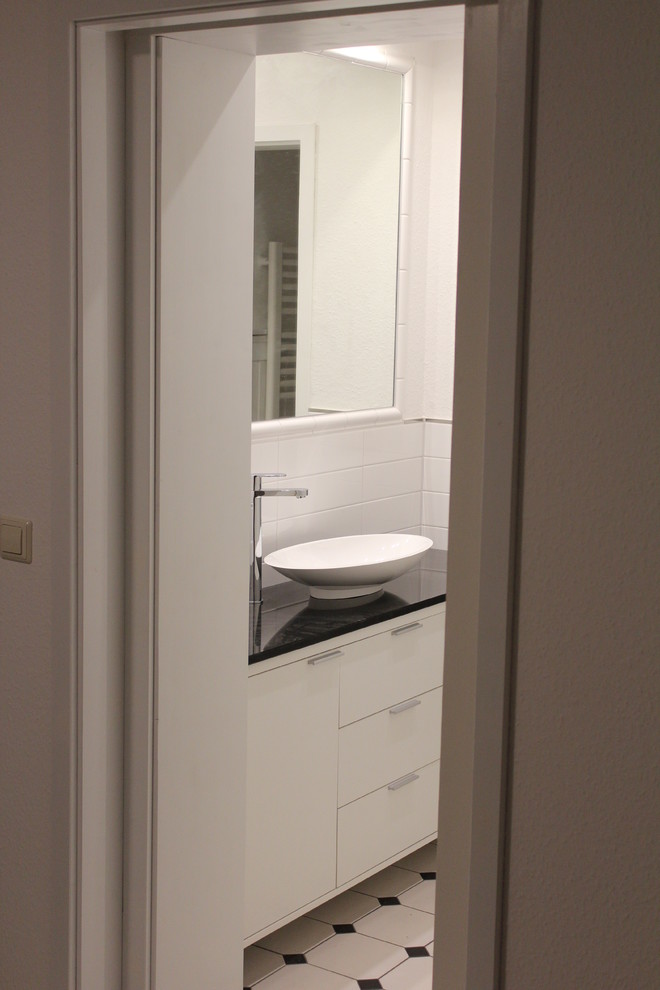 Idéer för ett litet lantligt badrum med dusch, med släta luckor, vita skåp, en kantlös dusch, en toalettstol med separat cisternkåpa, svart och vit kakel, vita väggar, klinkergolv i keramik, ett fristående handfat, granitbänkskiva och keramikplattor