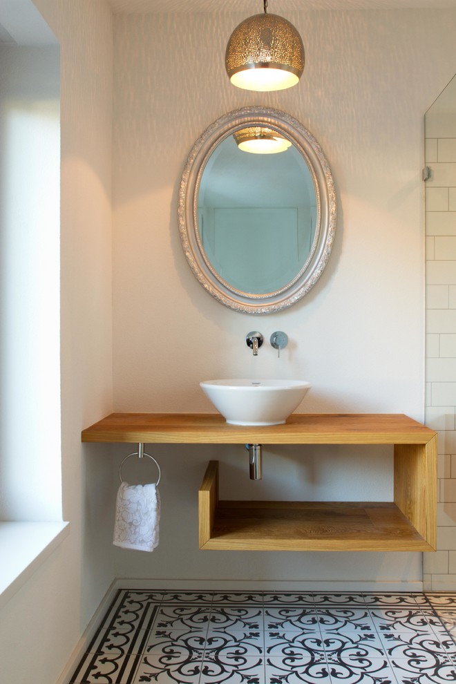 Inspiration för ett mellanstort funkis brun brunt badrum, med träbänkskiva, öppna hyllor, skåp i mellenmörkt trä, svart och vit kakel, vita väggar, klinkergolv i porslin och ett fristående handfat
