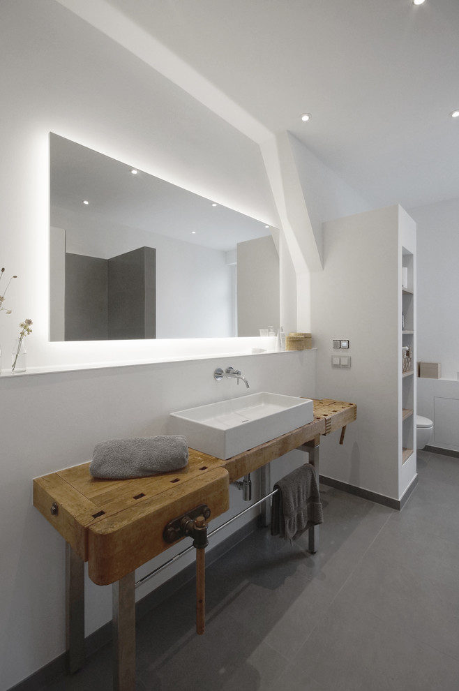 Ejemplo de cuarto de baño minimalista con paredes blancas, lavabo sobreencimera y encimera de madera