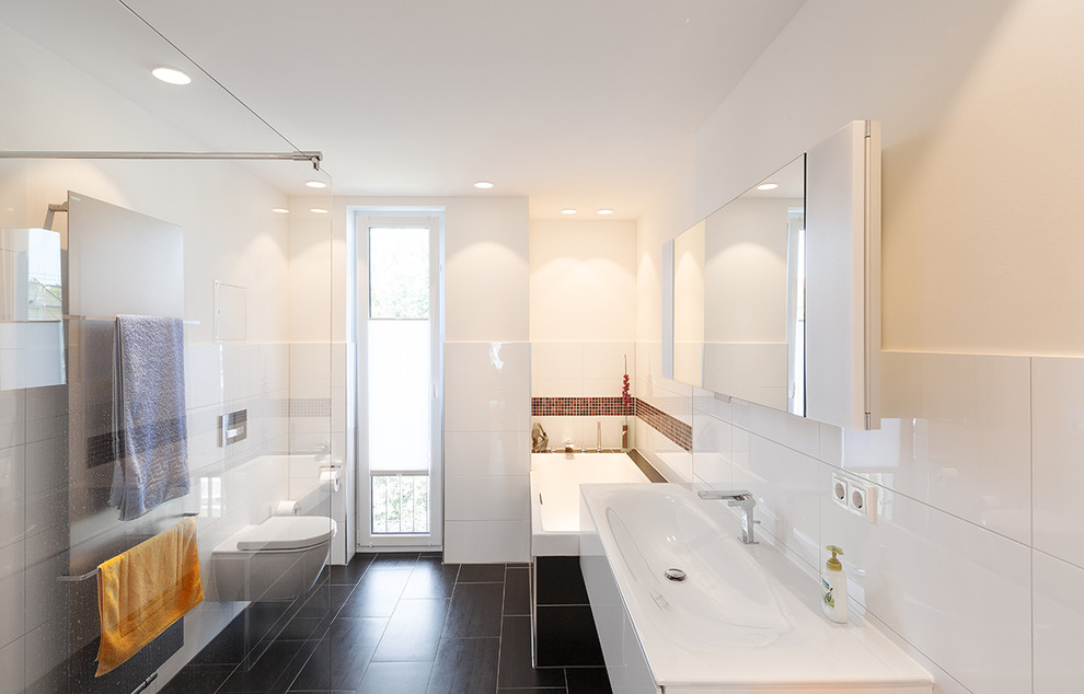 Großes Modernes Badezimmer mit Einbaubadewanne, schwarz-weißen Fliesen, weißer Wandfarbe, bodengleicher Dusche, Wandtoilette, Keramikfliesen und integriertem Waschbecken in Dresden