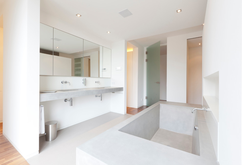 На фото: главная ванная комната среднего размера в стиле модернизм с монолитной раковиной, столешницей из бетона, белыми стенами и бетонным полом с