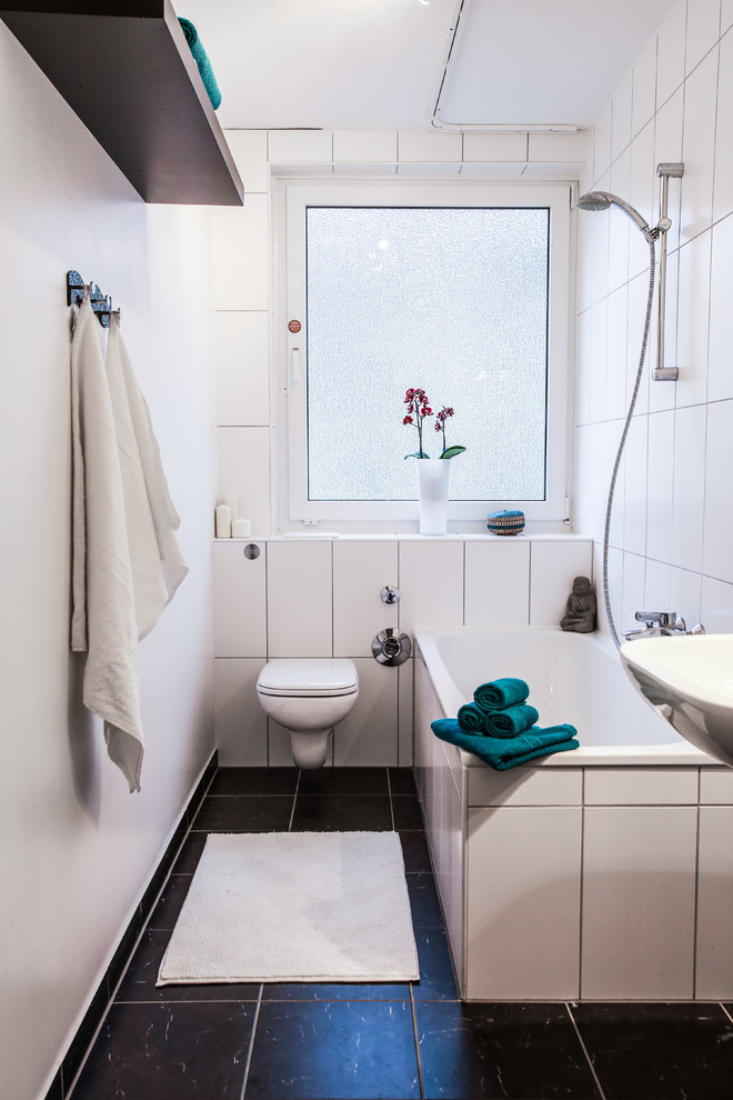 Inspiration för ett litet minimalistiskt badrum, med öppna hyllor, ett platsbyggt badkar, en dusch/badkar-kombination, en vägghängd toalettstol, svart och vit kakel, vita väggar, keramikplattor och med dusch som är öppen