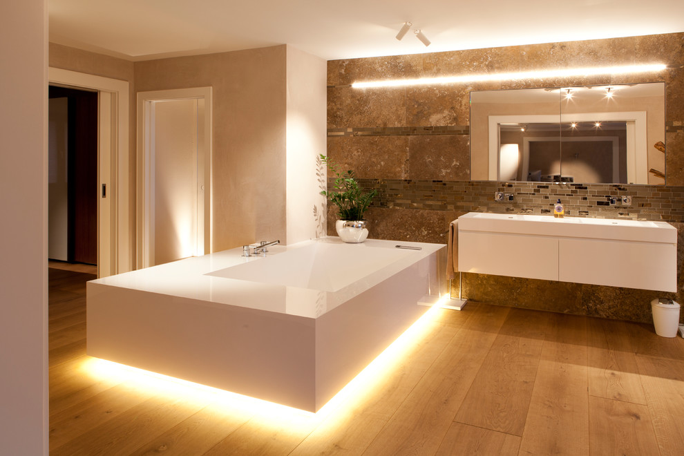 Aménagement d'une grande salle de bain principale contemporaine avec un placard à porte plane, des portes de placard blanches, un carrelage marron, un mur beige, un sol en bois brun, une baignoire indépendante, un lavabo suspendu et un sol jaune.