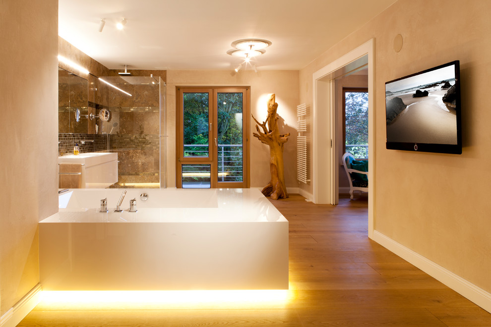Diseño de cuarto de baño contemporáneo grande con puertas de armario blancas, bañera encastrada, baldosas y/o azulejos marrones, paredes beige, suelo de madera en tonos medios y suelo marrón