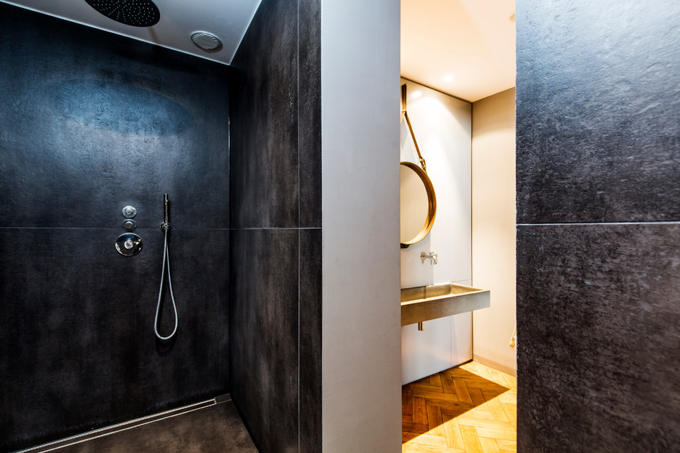 На фото: главная ванная комната среднего размера в современном стиле с открытым душем, черной плиткой, белыми стенами, паркетным полом среднего тона, подвесной раковиной, столешницей из бетона, открытыми фасадами, инсталляцией, коричневым полом и открытым душем