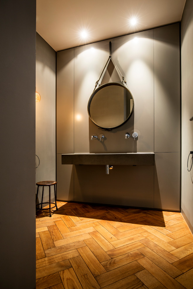 ミュンヘンにある高級な中くらいなコンテンポラリースタイルのおしゃれなマスターバスルーム (無垢フローリング、壁付け型シンク、コンクリートの洗面台、オープンシェルフ、オープン型シャワー、壁掛け式トイレ、黒いタイル、白い壁、茶色い床、オープンシャワー) の写真