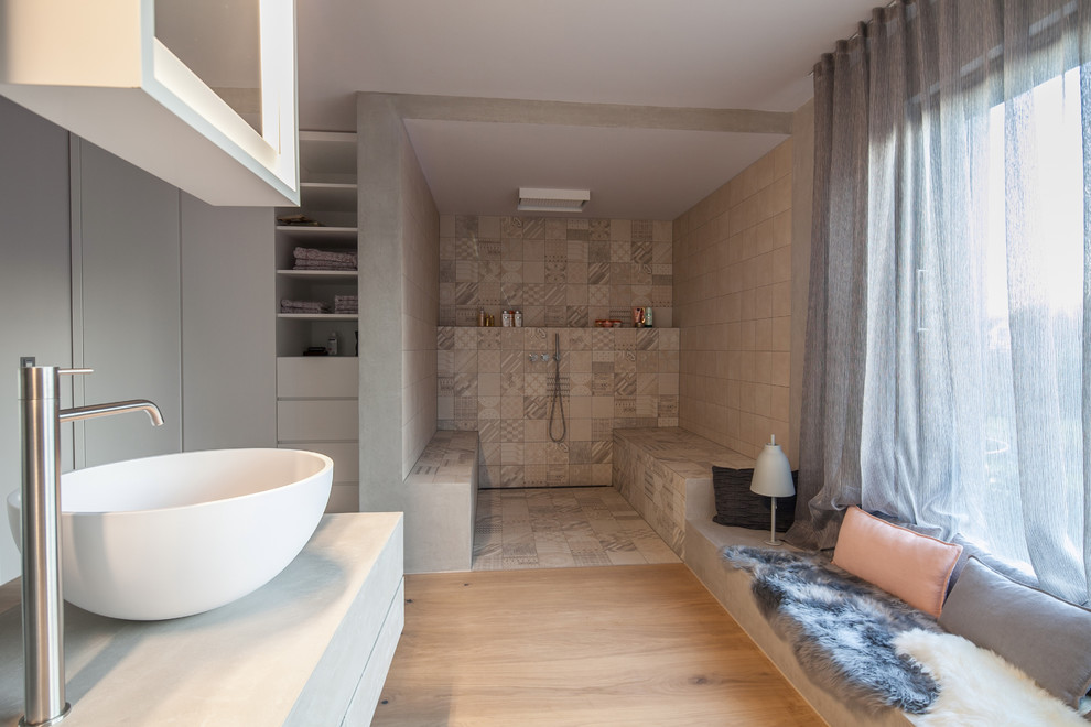 Exempel på ett stort modernt en-suite badrum, med släta luckor, vita skåp, ett platsbyggt badkar, en kantlös dusch, en vägghängd toalettstol, grå kakel, cementkakel, grå väggar, ljust trägolv, ett fristående handfat, bänkskiva i betong, beiget golv och med dusch som är öppen