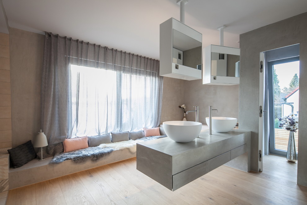 Idéer för att renovera ett mellanstort funkis en-suite badrum, med öppna hyllor, vita skåp, ett platsbyggt badkar, en kantlös dusch, en vägghängd toalettstol, blå kakel, keramikplattor, grå väggar, ljust trägolv, ett väggmonterat handfat, bänkskiva i betong, brunt golv och med dusch som är öppen