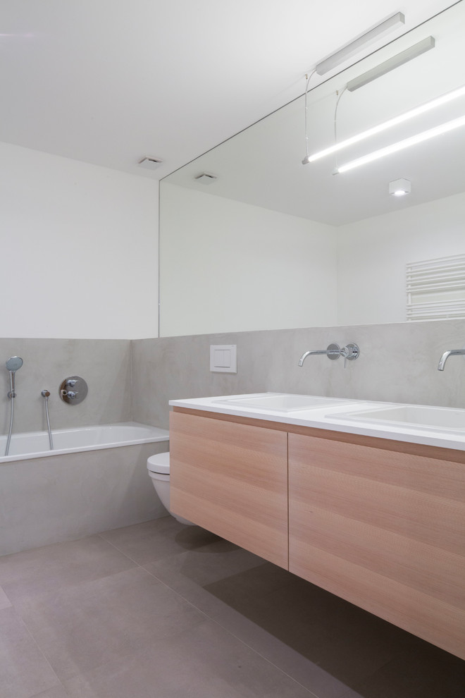Пример оригинального дизайна: ванная комната среднего размера в современном стиле с плоскими фасадами, светлыми деревянными фасадами, накладной ванной, раздельным унитазом, серой плиткой, белыми стенами, душевой кабиной, накладной раковиной и серым полом