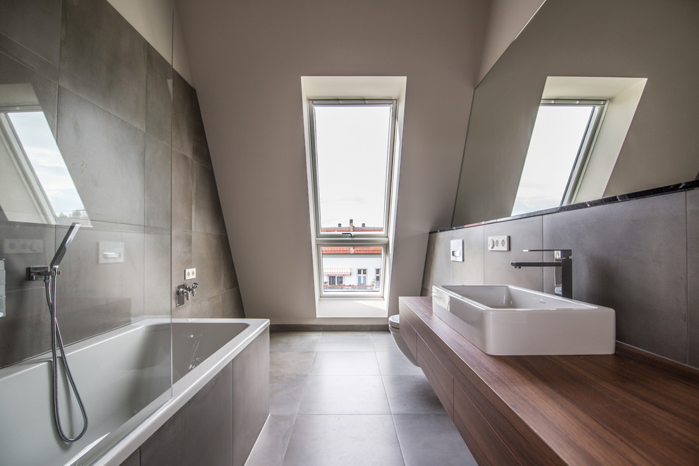 Medium sized contemporary ensuite bathroom in Berlin with flat-panel cabinets, a built-in bath, brown tiles, a vessel sink, wooden worktops, brown floors, medium wood cabinets, a shower/bath combination, brown walls and brown worktops.