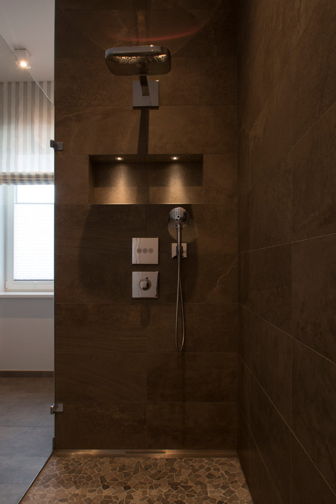 Photo of a medium sized contemporary shower room bathroom in Berlin with flat-panel cabinets, brown cabinets, a built-in shower, a wall mounted toilet, brown tiles, stone tiles, white walls, mosaic tile flooring, an integrated sink and solid surface worktops.