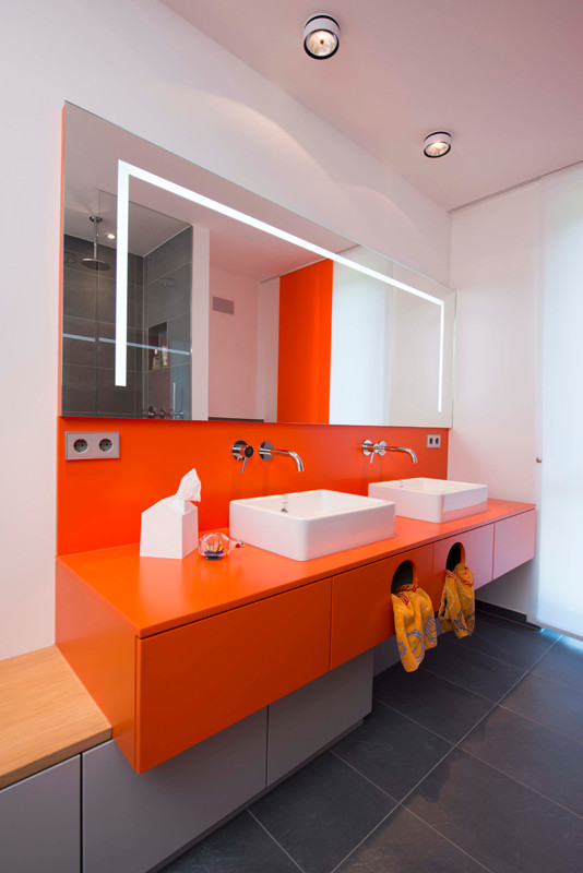 Modernes Kinderbad mit flächenbündigen Schrankfronten, orangefarbenen Schränken, weißer Wandfarbe und Aufsatzwaschbecken in München