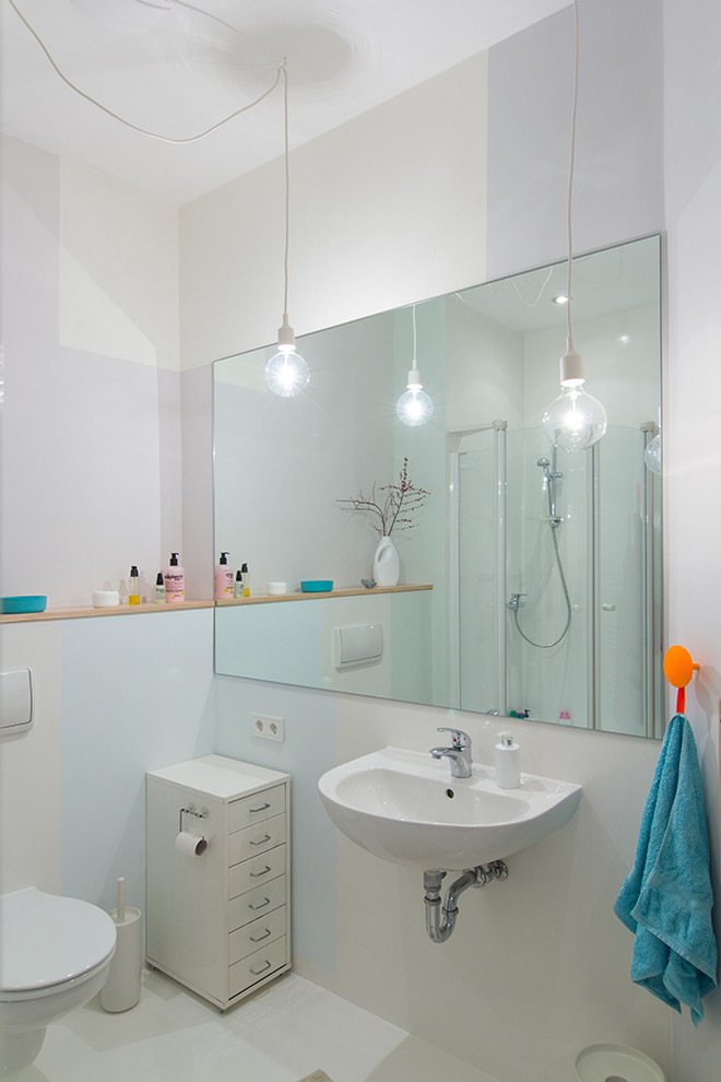 Photo of a small contemporary shower room bathroom in Berlin with flat-panel cabinets, white cabinets, a corner shower, a wall mounted toilet, white walls, ceramic flooring, a wall-mounted sink, white floors and a hinged door.